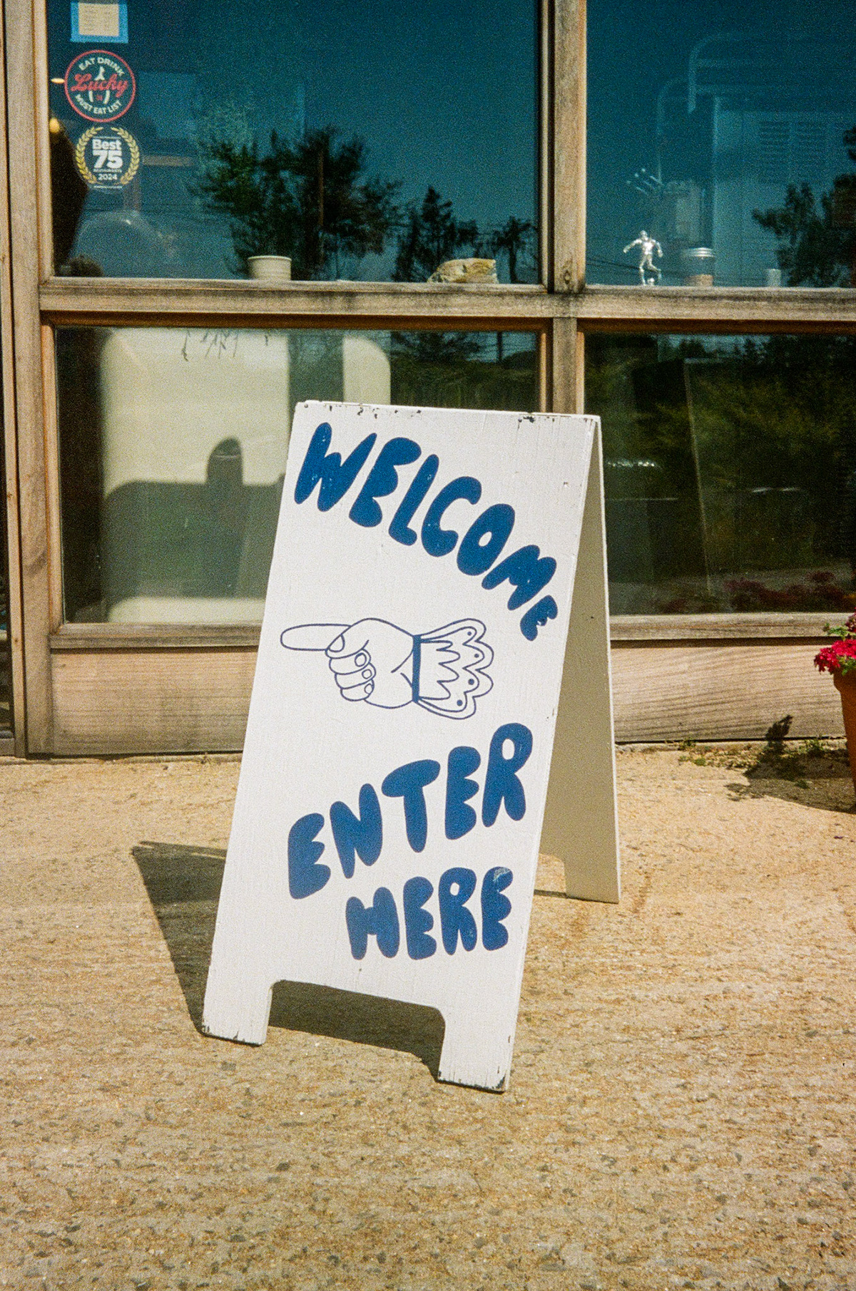 A hand-painted sign reading Welcome Enter Here outside a storefront